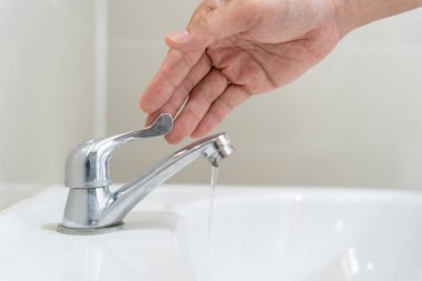 Su tasarrufu. Adam çevreyi korumak için tuvaletteki suyu kapatıp duruyor. Yeşillenen gezegen, küresel ısınmayı azalt Dünya 'yı, yaşamı, geleceği, risk enerjisini, krizi, su gününü kurtar.