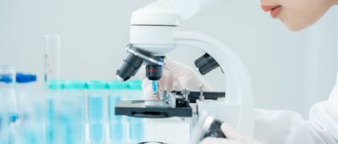 Bilimadamı ileri bilimsel laboratuvarda biyokimyasal örnekleri analiz ediyor. Tıbbi profesyonel kullanım mikroskobu virüsün mikrobiyolojik gelişimini gösteriyor. Fen laboratuvarında biyoteknoloji araştırması.