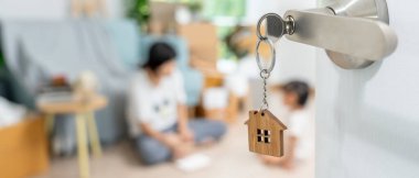 Taşınmak, taşınmak. Anahtar yeni evin kapısına yerleştirilmiş, odanın içinde kişisel eşyalar ve mobilyalar içeren bir karton kutu vardı. Daireye gir, afiş.