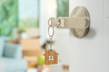Moving house, relocation. The key was inserted into the door of the new house, inside the room was a cardboard box containing personal belongings and furniture. move in the apartment or condominium