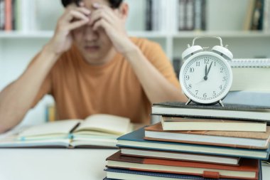 Öğrenci sınavlar yüzünden endişeli, erkek kütüphanede test ve öğrenme derslerine hazırlanıyor. Stres, umutsuzluk, acele, yanlış anlama okuma, cesaret kaybı, beklenti, bilgi, yorgunluk