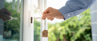 Evin kilidini açmak için ev sahibi anahtarı kapıya takılı. Kira ve satış için ikinci el ev. Sahibi yeni ev, satın al, sat, yenile, yatırım, sahip, mülk