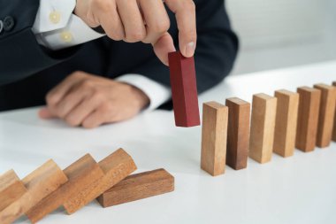 Domino 'yu elleri olan sigorta korur. İş adamı elleri iş krizinde domino taşlarının düşmesini durdurur. işletme risk denetimi ve planlama ve işletmeler sigorta işletmelerini önlemek için stratejiler.