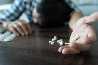 Asyalı erkek aşırı dozda hap kullanıyor, stresli, üzgün, uyuşturucu bağımlısı, uyuşturucu bağımlısı, hasta, sağlıksız, mutsuz, intihar, depresyonda veya umutsuz, uyuşturucu bağımlısı, yaşam ve aile sorunları, motivasyonsuz