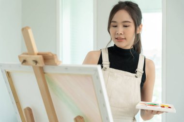 beautiful female hobbies about artist and use paintbrush in abstract art for create masterpiece. painter paint with watercolors or oil in studio house. enjoy painting as hobby, recreation, inspiration