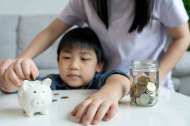 Para biriktir. Anne ve çocuklar domuz kumbarasını kurtarmak için tutuyorlar. wealth, Finans, Sigorta, Yatırım, Eğitim, Gelecek, Planlama Hayatı, Öğrenme, Bankacılık, Aile, Sağlık, Sağlık ve Kaza Sigorta