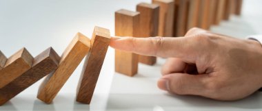 insurance with hands protect domino. Businessman hands stop dominoes falling in house crisis. business risk control and planning and strategies to run prevent insurance businesses.