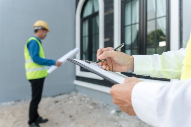 inspector or engineer is inspecting construction and quality assurance new house using a checklist. Engineers or architects or contactor work to build the house before handing it over to the homeowner