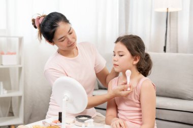 Anne mutlu çocuklar için makyaj yapıyor ve öğretmenlik yapıyor. Makyaj yapan kız. Aktivite ailesi, reklam, yaşam tarzı, kozmetik, makyaj malzemeleri, güzellik etkinliği, güzellik uzmanı, yetenek, aşk güzelliği.