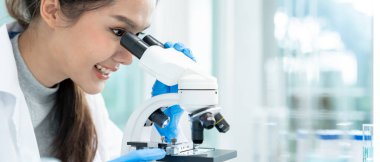 Bilimadamı ileri bilimsel laboratuvarda biyokimyasal örnekleri analiz ediyor. Tıbbi profesyonel kullanım mikroskobu virüsün mikrobiyolojik gelişimini gösteriyor. Fen laboratuvarında biyoteknoloji araştırması.