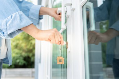 Evin kilidini açmak için ev sahibi anahtarı kapıya takılı. Kira ve satış için ikinci el ev. Sahibi yeni ev, satın al, sat, yenile, yatırım, sahip, mülk