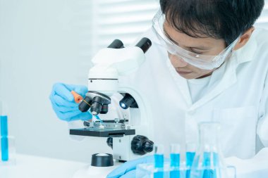 Bilimadamı ileri bilimsel laboratuvarda biyokimyasal örnekleri analiz ediyor. Tıbbi profesyonel kullanım mikroskobu virüsün mikrobiyolojik gelişimini gösteriyor. Fen laboratuvarında biyoteknoloji araştırması.