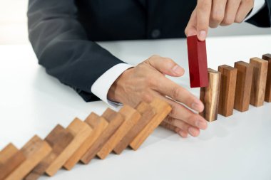 Domino 'yu elleri olan sigorta korur. İş adamı elleri iş krizinde domino taşlarının düşmesini durdurur. işletme risk denetimi ve planlama ve işletmeler sigorta işletmelerini önlemek için stratejiler.