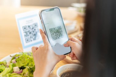 Woman use smartphone to scan QR code to pay in cafe restaurant with a digital payment without cash. Choose menu and order accumulate discount. E wallet, technology, pay online, credit card, bank app.