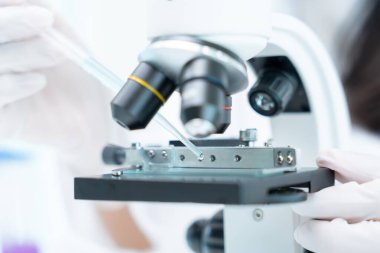 Bilimadamı ileri bilimsel laboratuvarda biyokimyasal örnekleri analiz ediyor. Tıbbi profesyonel kullanım mikroskobu virüsün mikrobiyolojik gelişimini gösteriyor. Fen laboratuvarında biyoteknoloji araştırması.