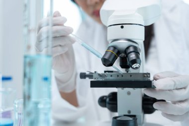 Bilimadamı ileri bilimsel laboratuvarda biyokimyasal örnekleri analiz ediyor. Tıbbi profesyonel kullanım mikroskobu virüsün mikrobiyolojik gelişimini gösteriyor. Fen laboratuvarında biyoteknoloji araştırması