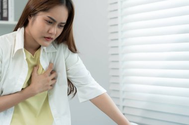 Kalp krizi belirtileri gösteren el ele tutuşmalar, çok çalışan Asyalı kadınların göğüs ağrıları kalp rahatsızlığı, sızıntı, genişleme, genişlemiş kalp, göğsüne acı veren ekspresyoyla baskı.