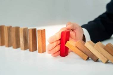 Domino 'yu elleri olan sigorta korur. İş adamı elleri iş krizinde domino taşlarının düşmesini durdurur. işletme risk denetimi ve planlama ve işletmeler sigorta işletmelerini önlemek için stratejiler