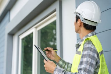 inspector or engineer is inspecting construction and quality assurance new house using a checklist. Engineers or architects or contactor work to build the house before handing it over to the homeowner