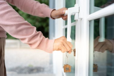 Evin kilidini açmak için ev sahibi anahtarı kapıya takılı. Kira ve satış için ikinci el ev. Sahibi yeni ev, satın al, sat, yenile, yatırım, sahip, mülk