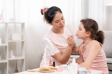 Anne mutlu çocuklar için makyaj yapıyor ve öğretmenlik yapıyor. Makyaj yapan kız. Aktivite ailesi, reklam, yaşam tarzı, kozmetik, makyaj malzemeleri, güzellik etkinliği, güzellik uzmanı, yetenek, aşk güzelliği.