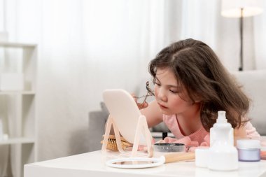 Kirpiklerini kıvır. Mutlu çocuklar yüz makyajının önünde otururlar. Reklam, yaşam tarzı, kozmetik, makyaj malzemeleri, güzellik aktiviteleri, güzellik uzmanı, yetenek, aşk güzelliği.