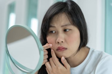 Genç Asyalı kadın, yüz dermatolojisi ve kozmetik ürünlerinde steroidlere alerjisi olduğu için endişeli. Hassas cilt, güneş yanığı, sivilce, kimyasallara alerjisi, yüzünde kızarıklık. cilt sorunları ve güzellik