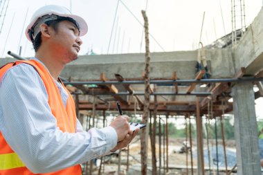 inspector or engineer is inspecting construction and quality assurance new house using a checklist. Engineers or architects or contactor work to build the house before handing it over to the homeowner