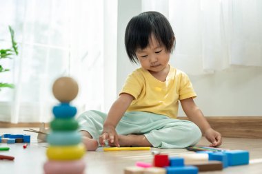 Mutlu Asyalı çocuk oyun oynuyor ve oyuncak bloklarını öğreniyor. Çocuklar evde çok mutlu ve heyecanlı. Çocuk oyun, etkinlik, gelişme ve dikkat eksikliği hiperaktivite bozukluğuyla çok iyi vakit geçiriyor