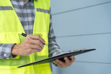 inspector or engineer is inspecting construction and quality assurance new house using a checklist. Engineers or architects or contactor work to build the house before handing it over to the homeowner