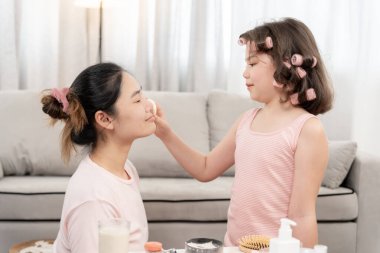 Mutlu çocuklar yüzlerinde ayna makyajı ile otururlar. Makyaj yapan kız. Reklam, yaşam tarzı, kozmetik, makyaj malzemeleri, güzellik etkinliği, güzellik uzmanı, yetenek, aşk güzelliği.