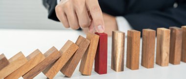 Domino 'yu elleri olan sigorta korur. İş adamı elleri iş krizinde domino taşlarının düşmesini durdurur. işletme risk denetimi ve planlama ve işletmeler sigorta işletmelerini önlemek için stratejiler