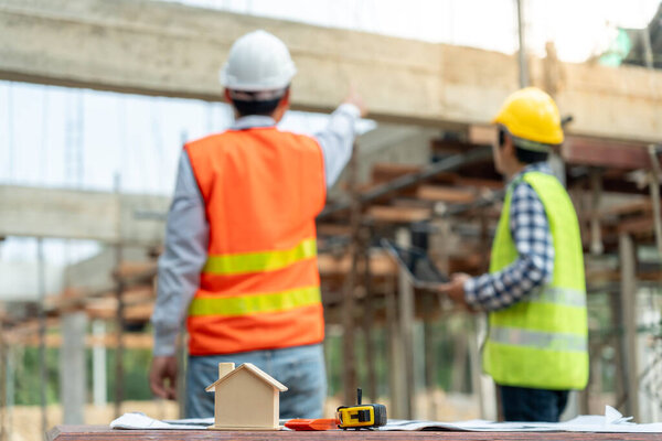 Инспектор или инженер проверяет строительство и обеспечение качества нового дома с помощью компьютера. Инженеры, архитекторы или подрядчики строят дом, прежде чем передать его домовладельцу.