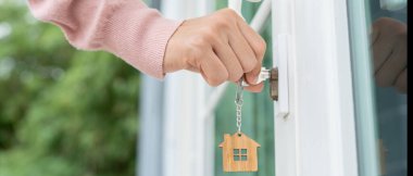 Evin kilidini açmak için ev sahibi anahtarı kapıya takılı. Kira ve satış için ikinci el ev. Sahibi yeni ev, satın al, sat, yenile, yatırım, sahip, mülk