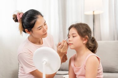 Anne mutlu çocuklar için makyaj yapıyor ve öğretmenlik yapıyor. Makyaj yapan kız. Aktivite ailesi, reklam, yaşam tarzı, kozmetik, makyaj malzemeleri, güzellik etkinliği, güzellik uzmanı, yetenek, aşk güzelliği.