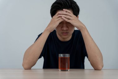 Depresyondaki genç Asyalı adam evde yalnız başına viski içmenin kötü hissettirdiğini, alkol içmenin sorunlu içki, alkolizm, hayat ve aile probleminden muzdarip olduğunu vurguladı.