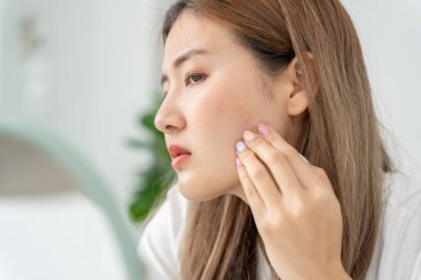 Genç Asyalı kadın, yüz dermatolojisi ve kozmetik ürünlerinde steroidlere alerjisi olduğu için endişeli. Hassas cilt, güneş yanığı, sivilce, kimyasallara alerjisi, yüzünde kızarıklık. cilt sorunları ve güzellik
