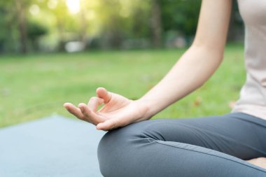 Kadın parkta meditasyon yapıyor. Sabahları egzersiz yapan Asyalı bir kadın. denge, dinlenme, rahatlama, sakinlik, sağlık, mutluluk, rahatlama, sağlıklı yaşam tarzı, stresi azaltma, huzur, tutum.