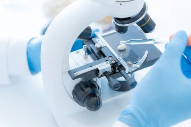 Bilimadamı ileri bilimsel laboratuvarda biyokimyasal örnekleri analiz ediyor. Tıbbi profesyonel kullanım mikroskobu virüsün mikrobiyolojik gelişimini gösteriyor. Fen laboratuvarında biyoteknoloji araştırması