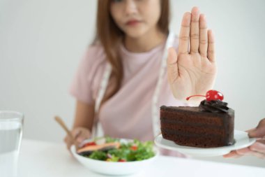 Beauty slim female body confuse chocolate cake. Woman in restaurant achieves weight loss goal for healthy life, crazy about thinness, thin waist, nutritionist. Diet, body shape.