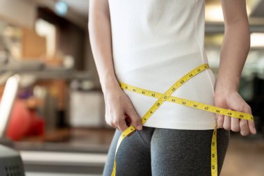 Diyet ve diyet. Güzel, ince kadın vücut ölçüsü. Spor elbiseli bir kadın sağlıklı yaşam için kilo verme hedefine, zayıflığa, ince belliye, beslenme uzmanına ulaşır..