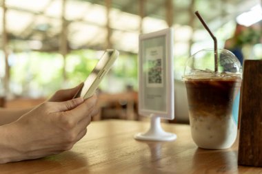 Woman use smartphone to scan QR code to pay in cafe restaurant with a digital payment without cash. Choose menu and order accumulate discount. E wallet, technology, pay online, credit card, bank app.