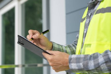 inspector or engineer is inspecting construction and quality assurance new house using a checklist. Engineers or architects or contactor work to build the house before handing it over to the homeowner