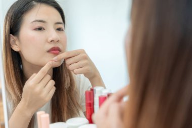 Genç Asyalı kadın, yüz dermatolojisi ve kozmetik ürünlerinde steroidlere alerjisi olduğu için endişeli. Hassas cilt, güneş yanığı, sivilce, kimyasallara alerjisi, yüzünde kızarıklık. cilt sorunları ve güzellik