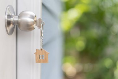 Landlord key for unlocking house is plugged into the door. Second hand house for rent and sale. keychain is blowing in the wind. mortgage for new home, buy, sell, renovate, investment, owner, estate
