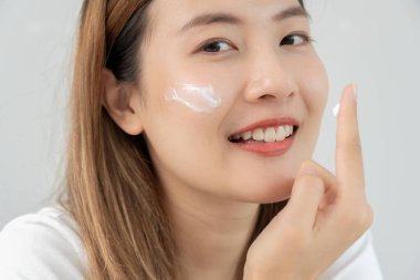 Güzel bir kadın aynanın önünde oturur. Krem sürerek makyaj yapan sağlıklı bir kadın yüzü. Cilt kremi reklamı, kırışıklık önleyici, bebek yüzü, beyazlatma, nemlendirici, gözenekleri sıkma seru