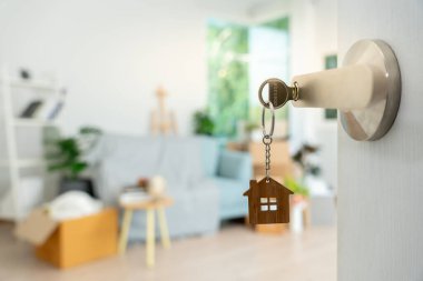 Moving house, relocation. The key was inserted into the door of the new house, inside the room was a cardboard box containing personal belongings and furniture. move in the apartment or condominium
