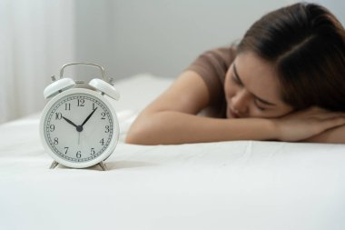 Tembel Asya 'lı genç kadın saat alarmını kapatıyor, bayan geç kalıyor ya da işe gidiyor ya da ders çalışıyor, uyuyakalıyor, sabahları uyanıyor, endişeleniyor, uykulu, geç kalmış, acele et.