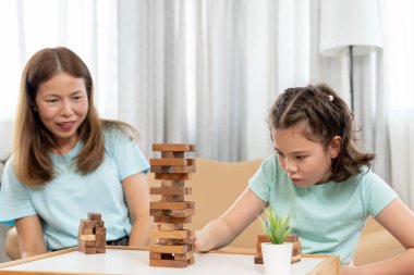 Asya 'lı mutlu anne küçük kızla Jan-ga oyunu oynuyor. Komik aile evde mutlu ve heyecanlı. Anne ve oğlu birlikte vakit geçiriyorlar. Tatil, hafta sonu, boş.