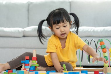 Mutlu Asyalı çocuk oyun oynuyor ve oyuncak bloklarını öğreniyor. Çocuklar evde çok mutlu ve heyecanlı. Çocuk oyun, etkinlik, gelişme ve dikkat eksikliği hiperaktivite bozukluğuyla çok iyi vakit geçiriyor